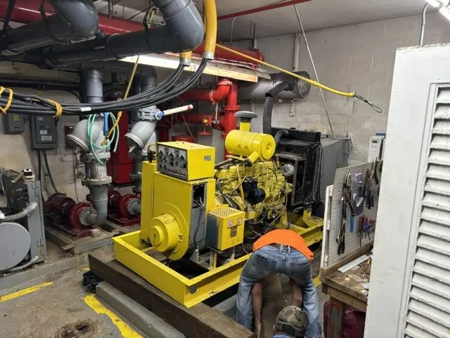 Commercial standby generator on a steel skid inside a building mechanical room