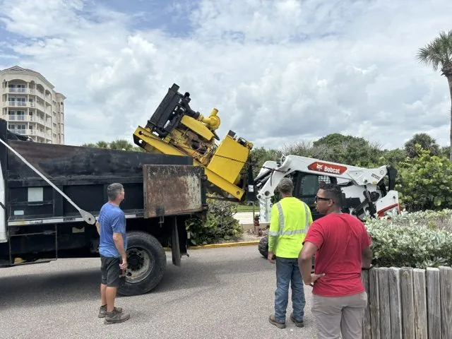 Crane lifting a generator onto a truck at a beachside property during a Wavelength Electric job