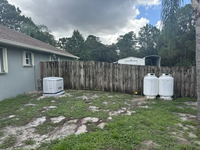 Generac standby generator installed beside a home with two propane tanks