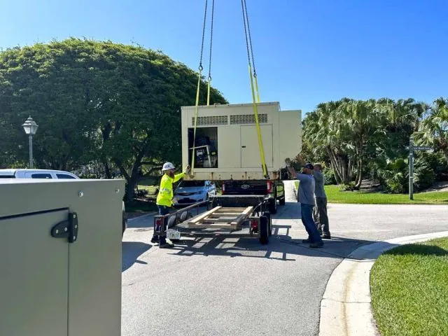 Crane lifting a large generator onto a trailer during a generator installation
