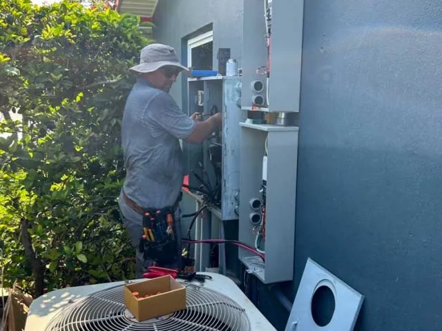 Electrician wiring meter and electrical panels on the exterior wall of a house