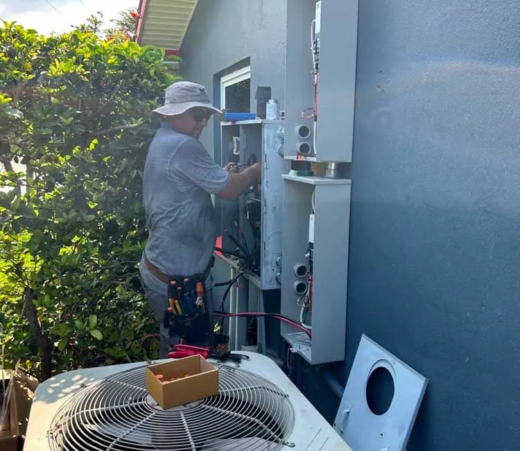 Electrician wiring meter and electrical panels on the exterior wall of a house