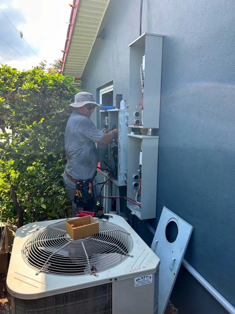 Electrician wiring meter and electrical panels on the exterior wall of a house