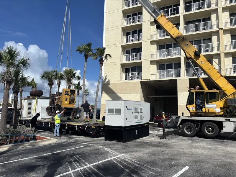 Crane setting a new commercial standby generator beside a condominium tower in Brevard County, FL