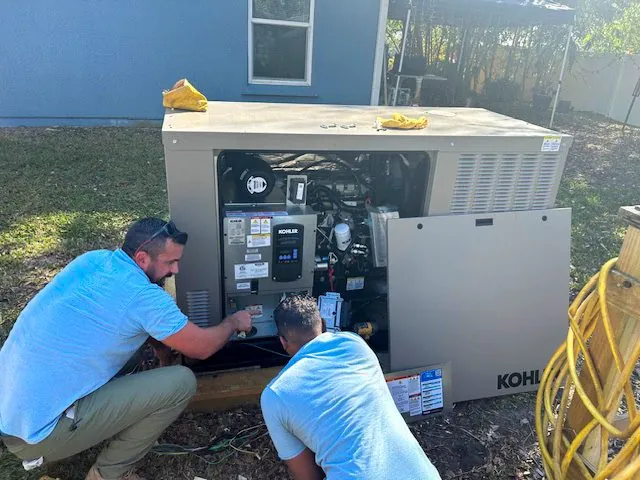 Technicians servicing an open Kohler home generator