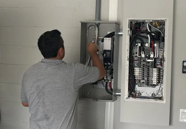 Electrician in Melbourne, FL wiring a circuit breaker panel