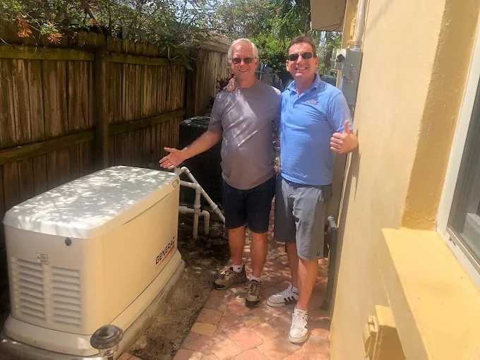 Homeowner with a Wavelength electrician beside a newly installed Generac generator