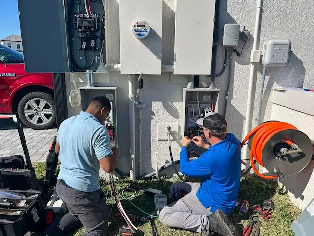 Two electricians working on an outdoor electrical panel system